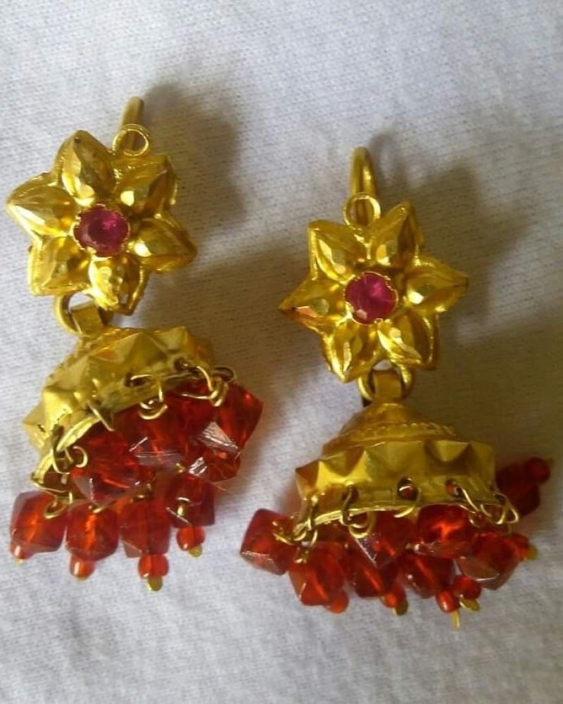 Jhumka earrings with a filigree top and pearl-like drops on a dark background